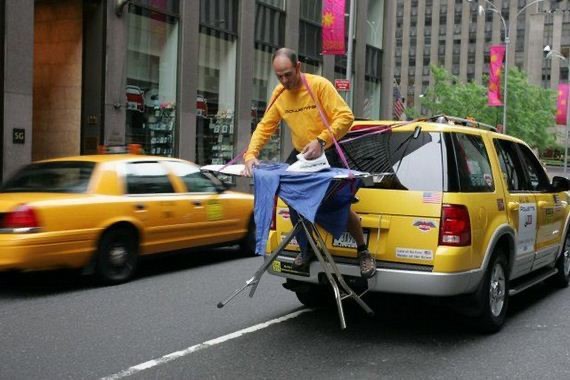 Original photo: a man standing on the back of a yellow taxi holding an iron.